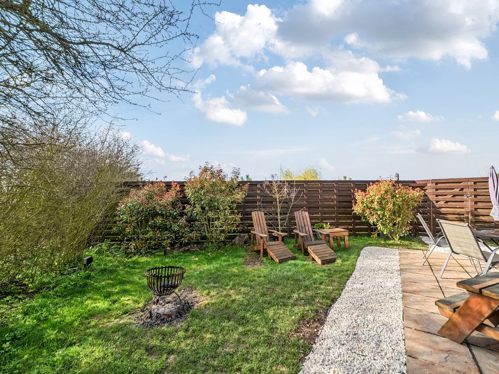 A garden with wooden chairs and a fire pit at Cosy Escape in Minster On Sea