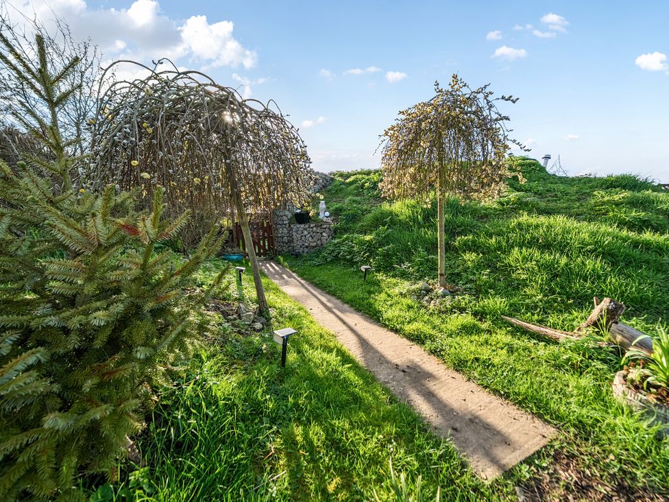 A garden with a pathway and decorative trees at Cosy Escape in Minster On Sea