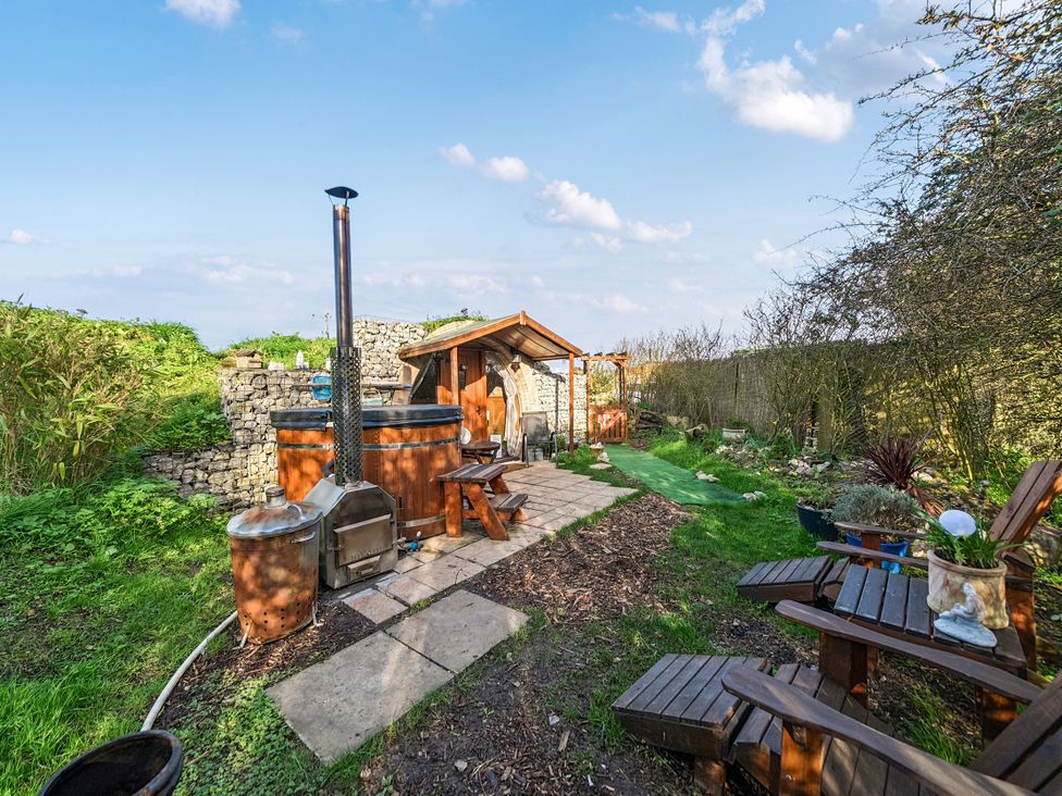 A garden with a wooden hot tub and seating area at Cosy Escape in Minster On Sea