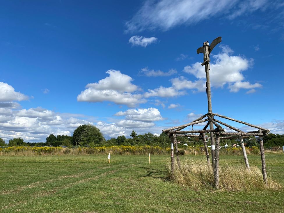 A wooden structure in a grassy area with a blue sky at Cotswold Nights Away in Evesham