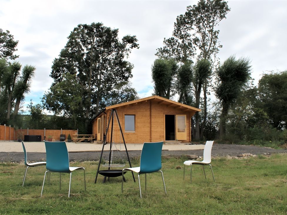 An outdoor area with a wooden cabin and chairs at Cotswold Nights Away Evesham