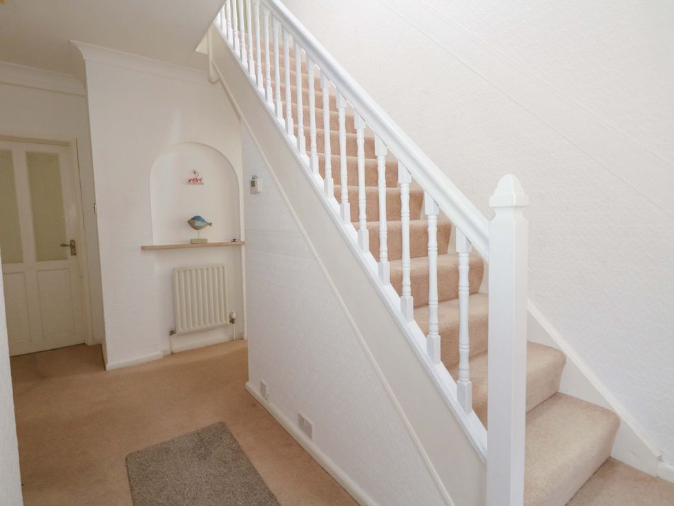 A hallway with a staircase and a shelf at 15 Coombe Avenue