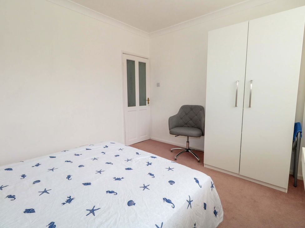 A bedroom with a bed, wardrobe, and chair at 15 Coombe Avenue
