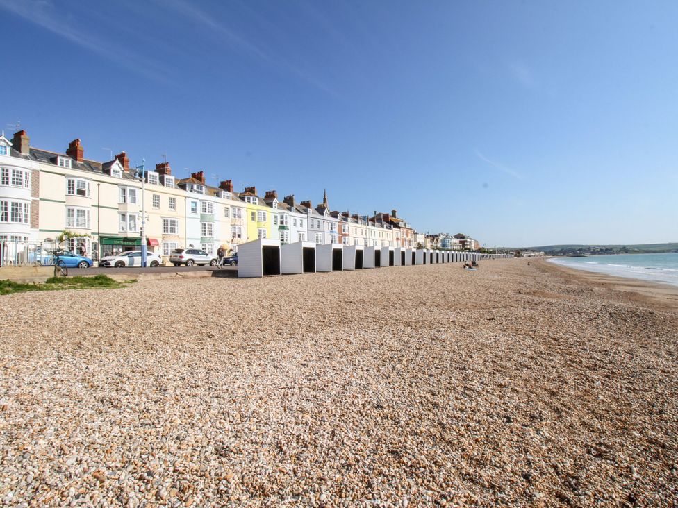 A beach view with houses and beach huts at 15 Coombe Avenue
