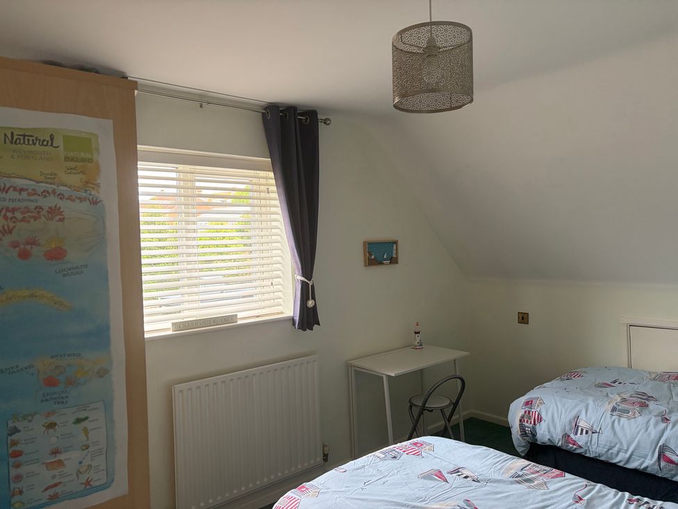 A bedroom with two beds and a table at Tudor Rose in Weymouth