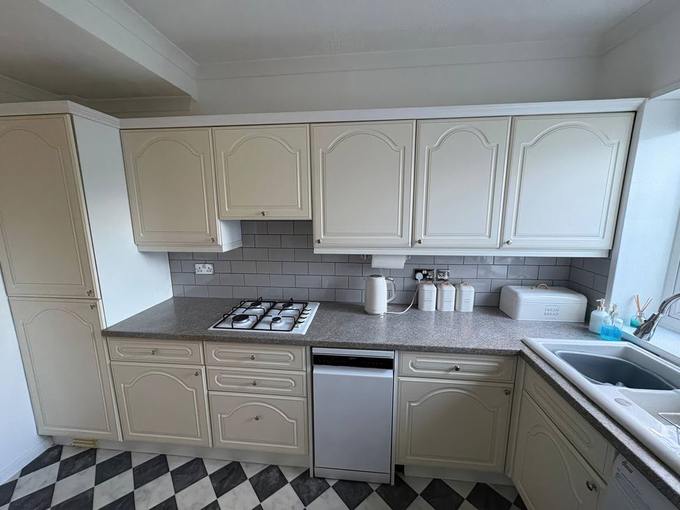A kitchen with cabinets and a gas stove at Tudor Rose in Weymouth