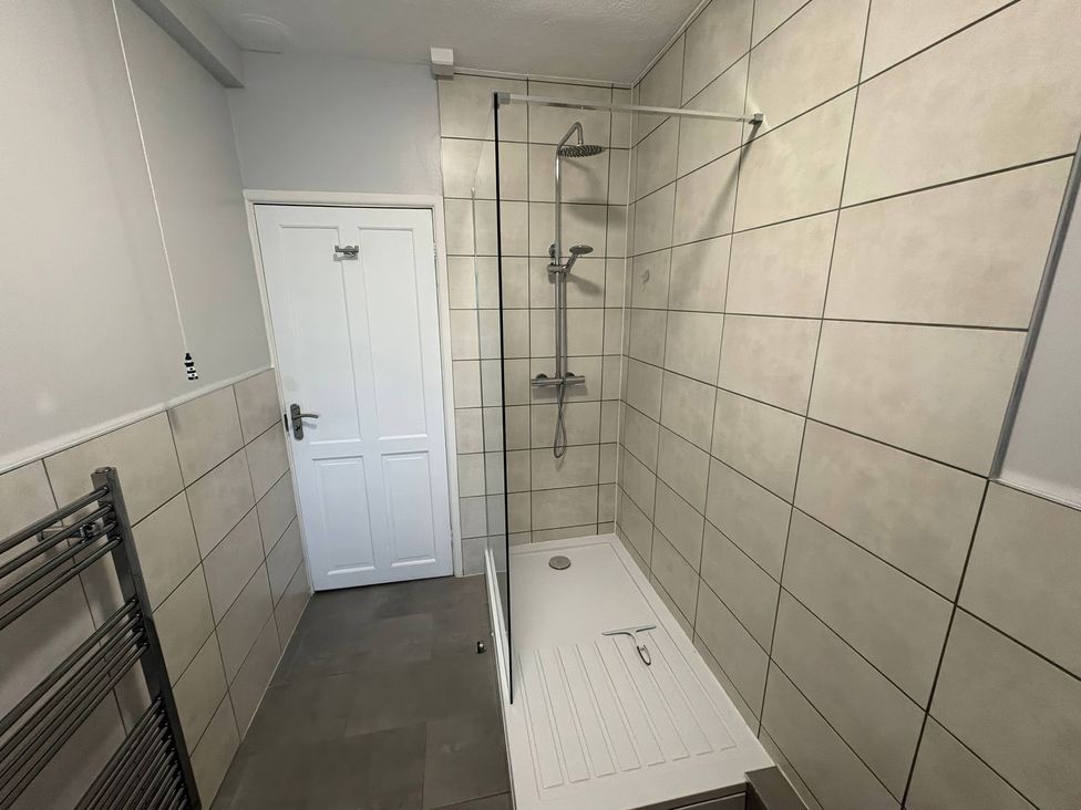 A bathroom with a walk-in shower and heated towel rail at Tudor Rose in Weymouth