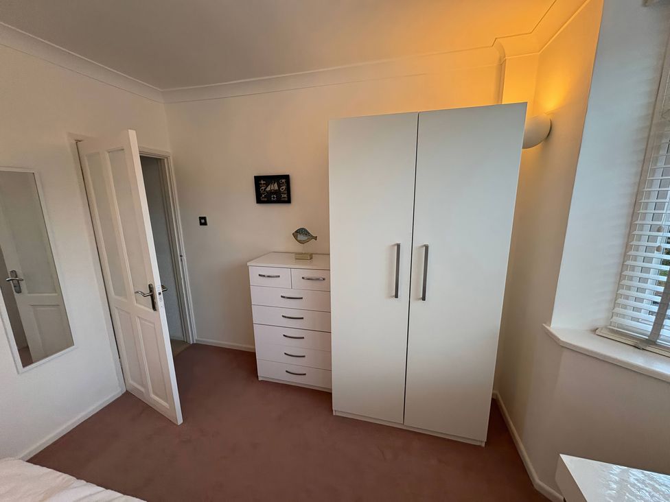 A bedroom with a wardrobe and chest of drawers at Tudor Rose in Weymouth