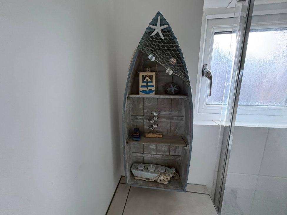 A shelf with decorative items in a bathroom at Tudor Rose in Weymouth