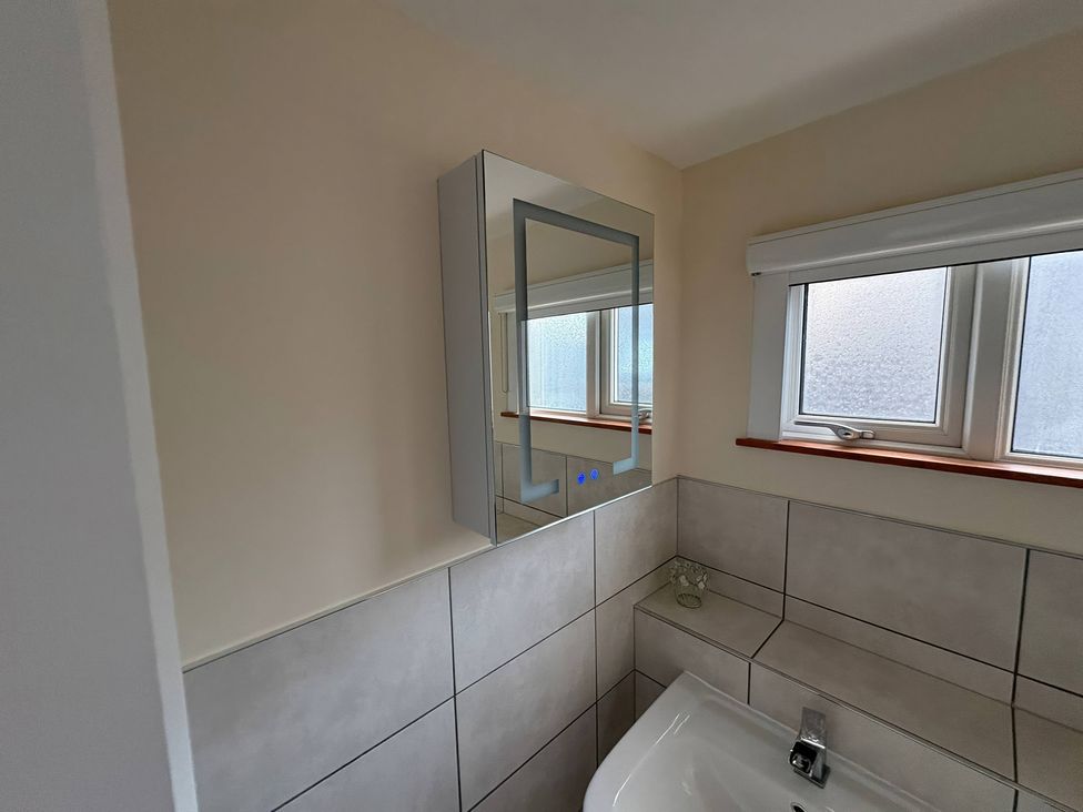 A bathroom with a mirror and sink at Tudor Rose in Weymouth