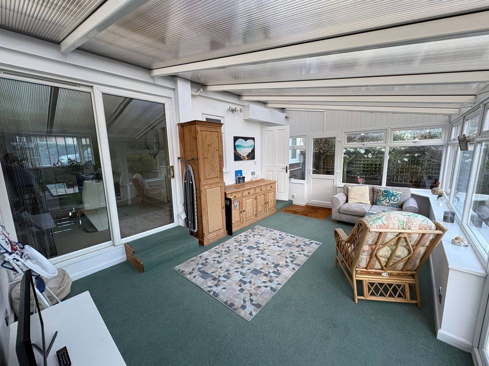 A conservatory with seating and a sideboard at Tudor Rose in Weymouth