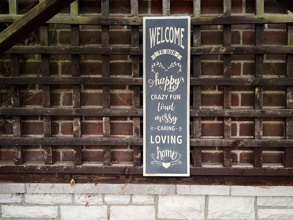 A welcome sign on a wooden trellis in an outdoor area at Tudor Rose in Weymouth