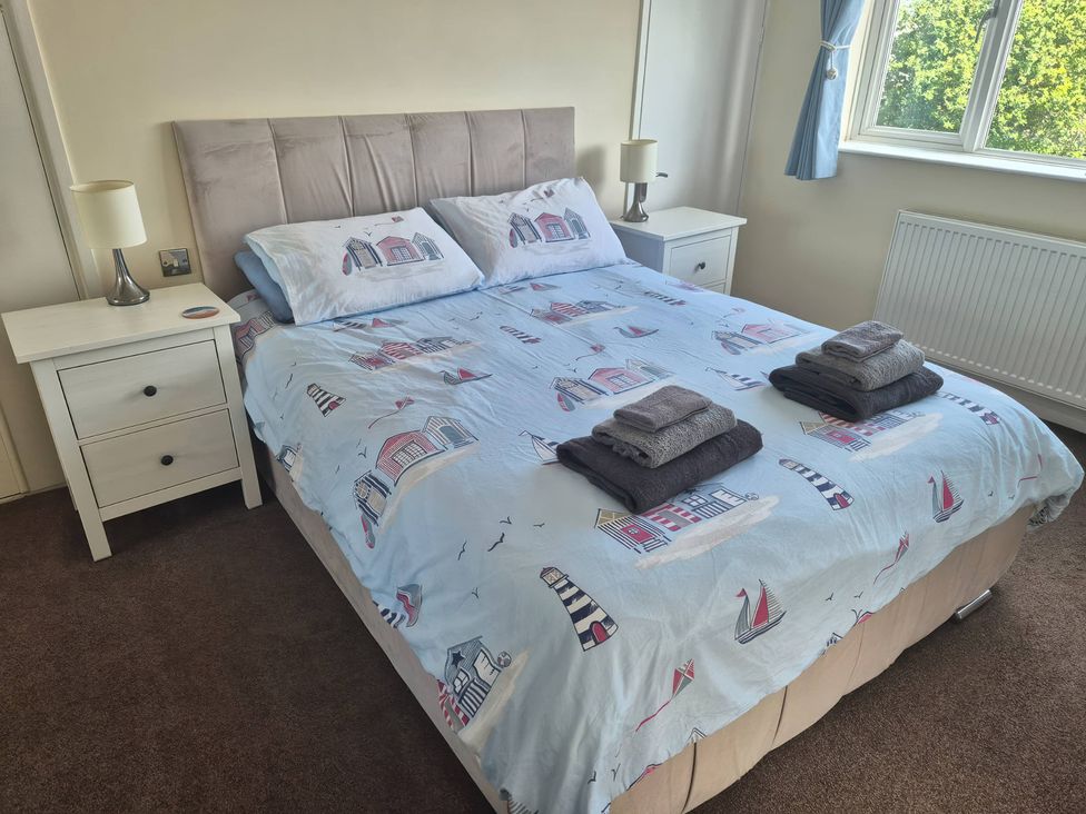 A bedroom with a bed and nightstand at Tudor Rose in Weymouth