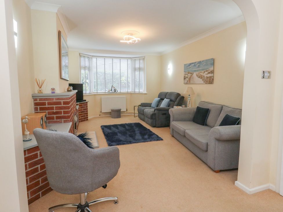 A living room with an armchair and sofa at Tudor Rose in Weymouth