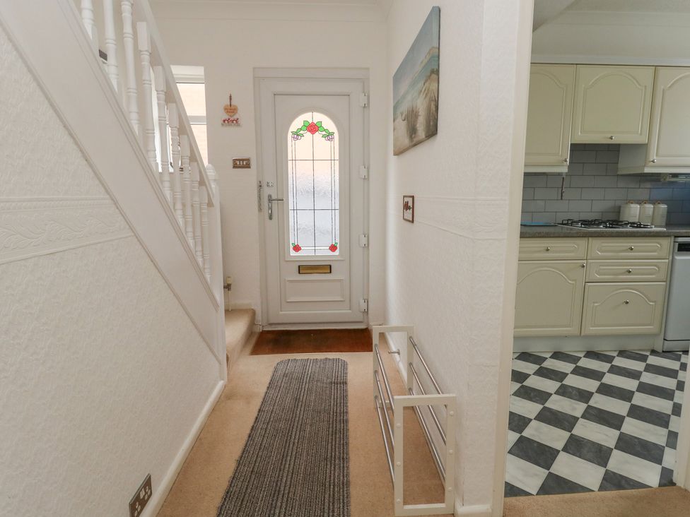 A hallway with a staircase and door at Tudor Rose in Weymouth