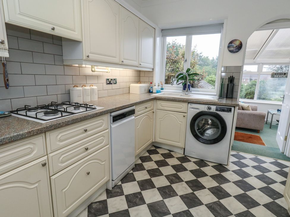 A kitchen with a gas stove, dishwasher, and washing machine at Tudor Rose in Weymouth