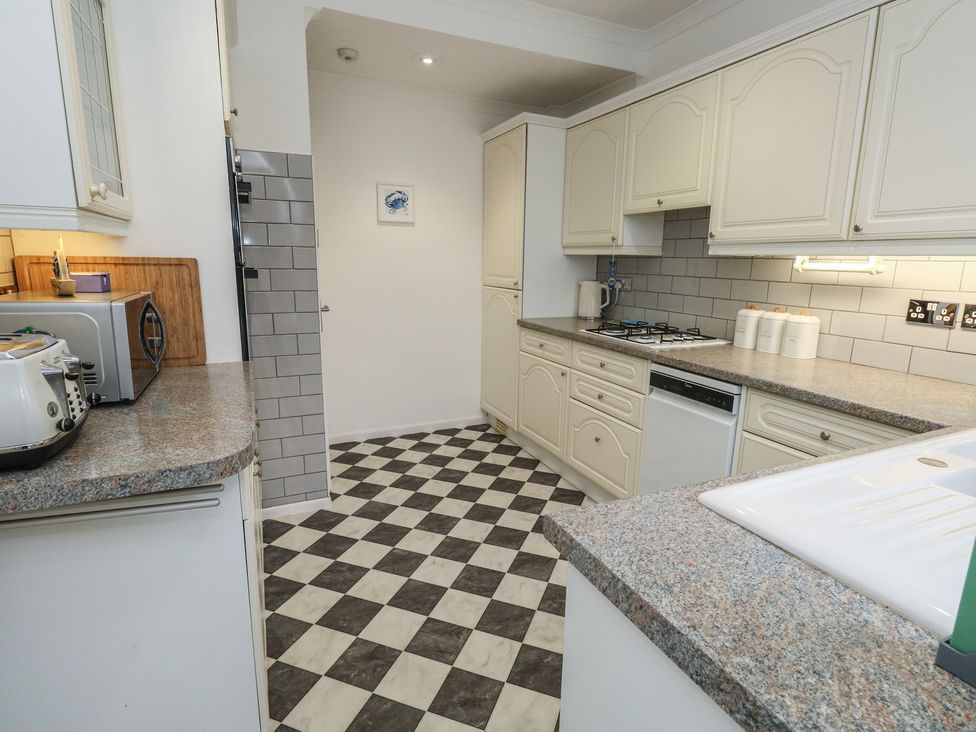 A kitchen with various appliances and cabinets at Tudor Rose in Weymouth