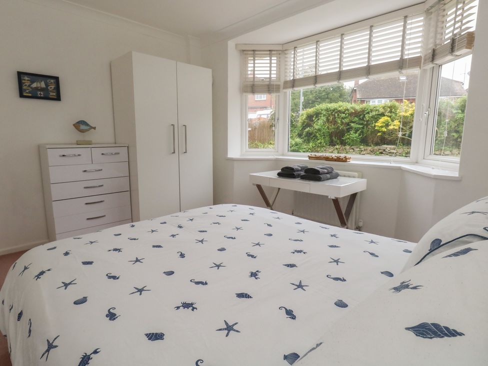 A bedroom with a bed, wardrobe, and dresser at Tudor Rose in Weymouth
