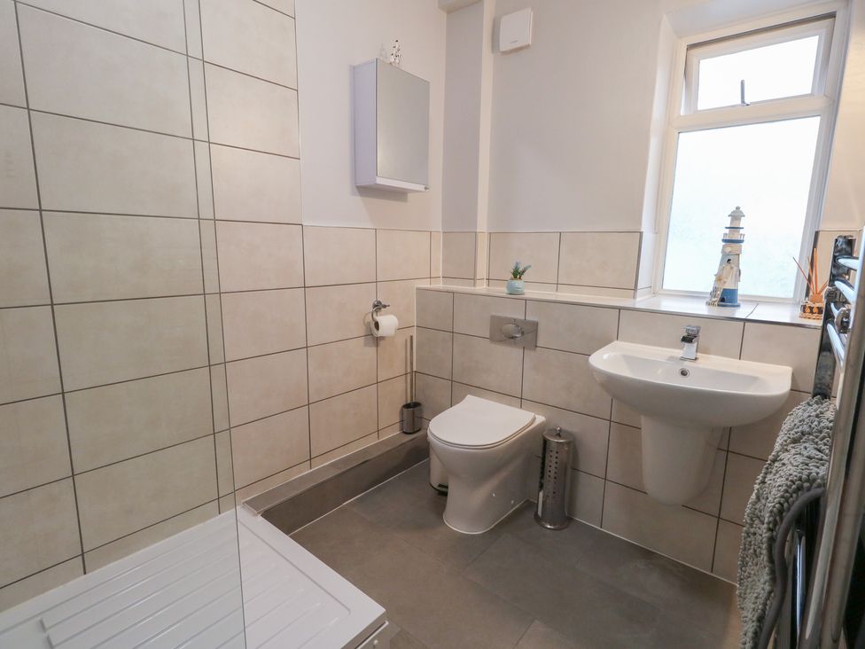 A bathroom with a sink, toilet, and shower base at Tudor Rose in Weymouth