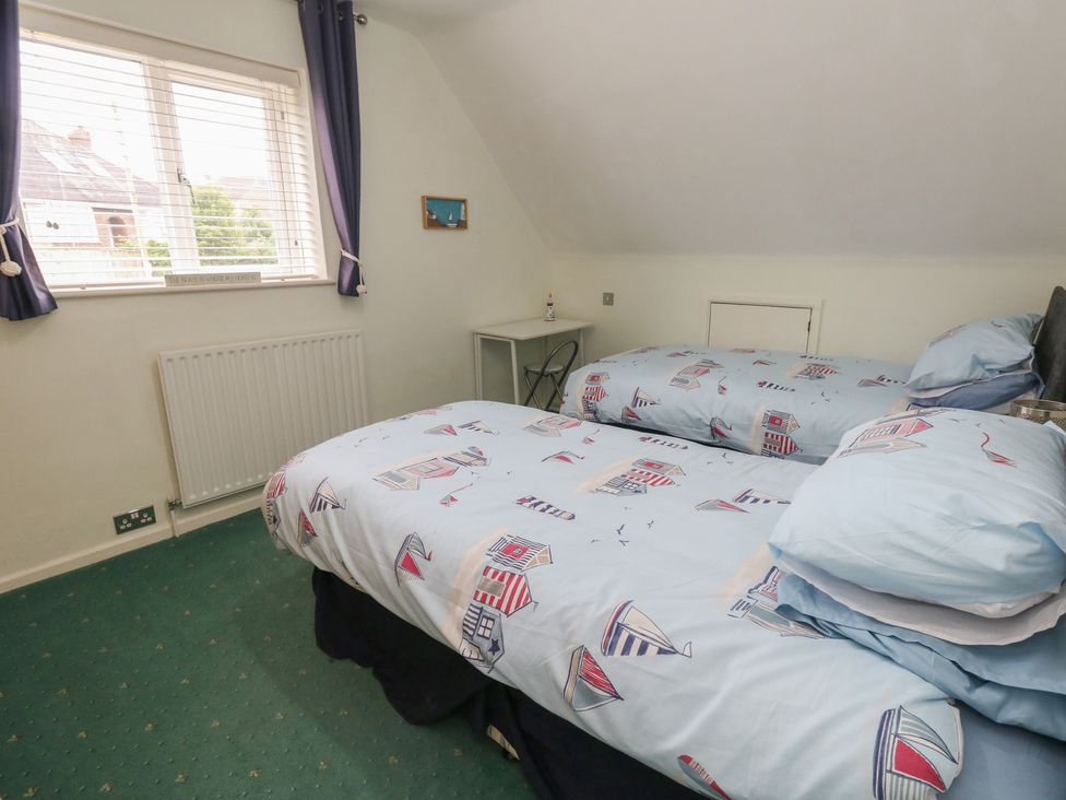 A bedroom with two beds and a bedside table at Tudor Rose in Weymouth