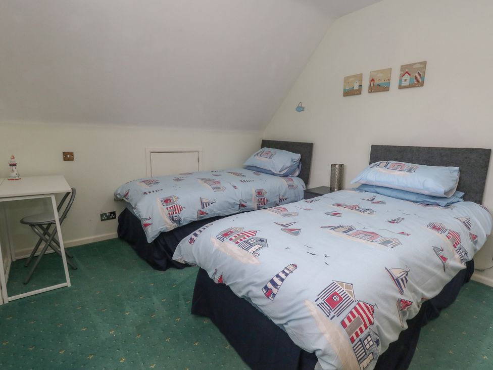 A bedroom with two beds and a desk at Tudor Rose in Weymouth