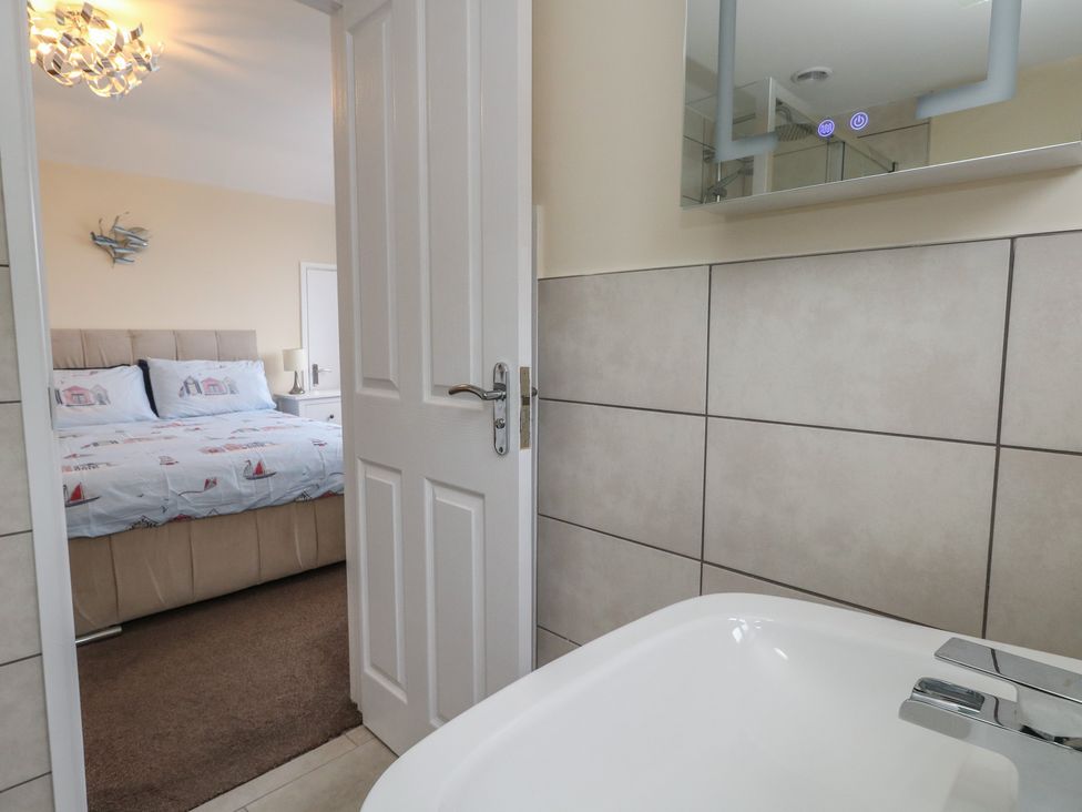 A bathroom with a bathtub and a view of a bedroom at Tudor Rose in Weymouth