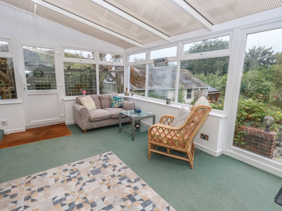 A conservatory with a sofa and coffee table at Tudor Rose in Weymouth