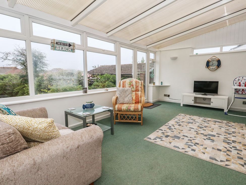 A conservatory with a sofa and coffee table at Tudor Rose in Weymouth