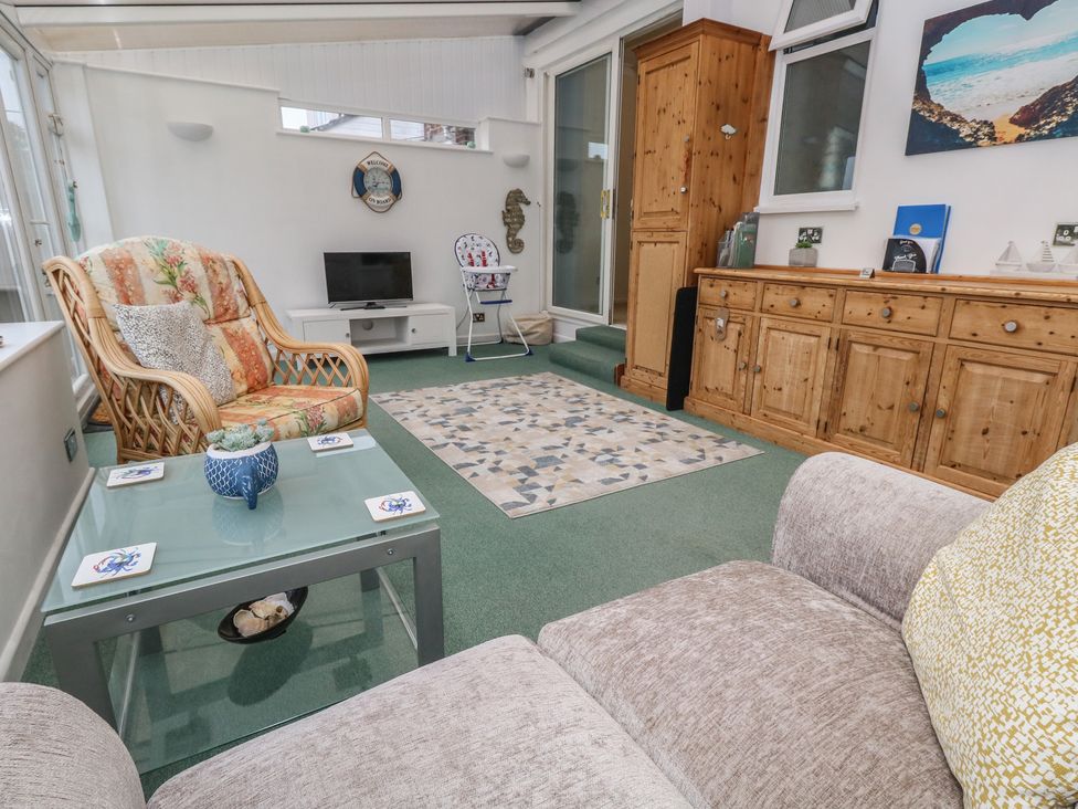 A conservatory with a sofa and television at Tudor Rose in Weymouth