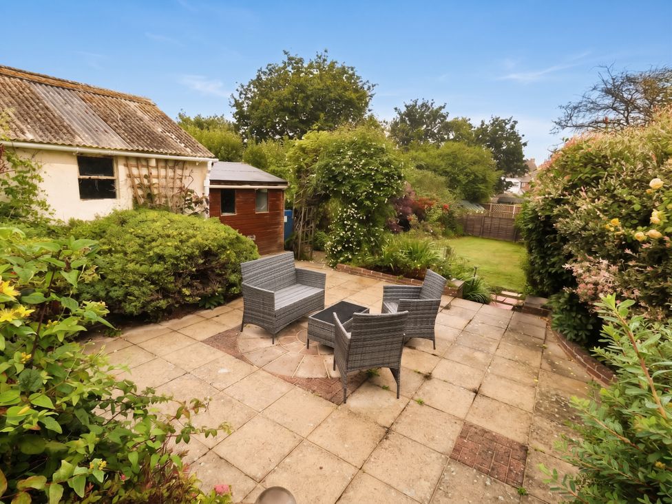 A garden with outdoor chairs and a table at Tudor Rose in Weymouth