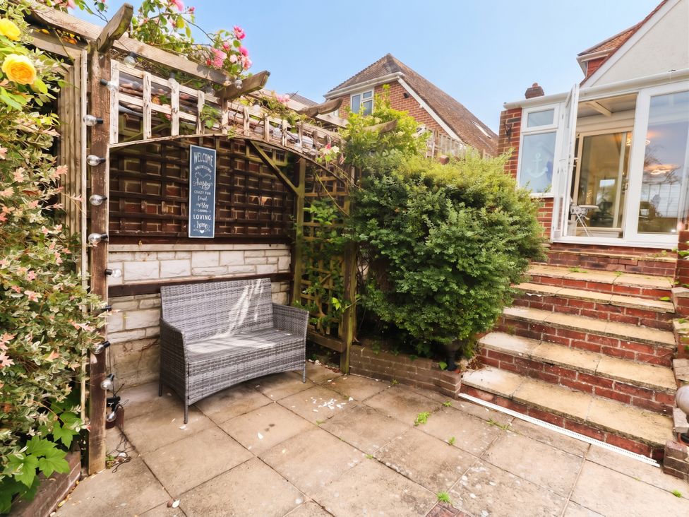 A garden with a bench and an archway at Tudor Rose in Weymouth