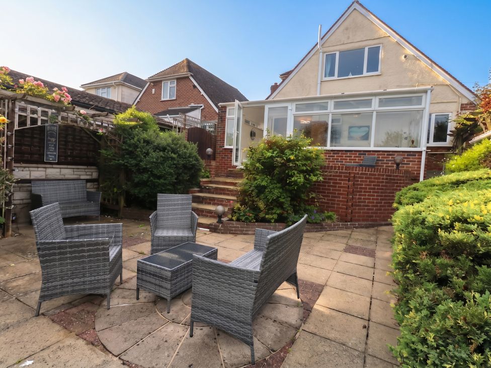A garden with a seating area and steps at Tudor Rose in Weymouth