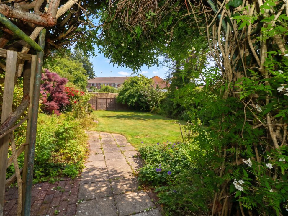 A garden with a pathway and flowering plants at Tudor Rose in Weymouth