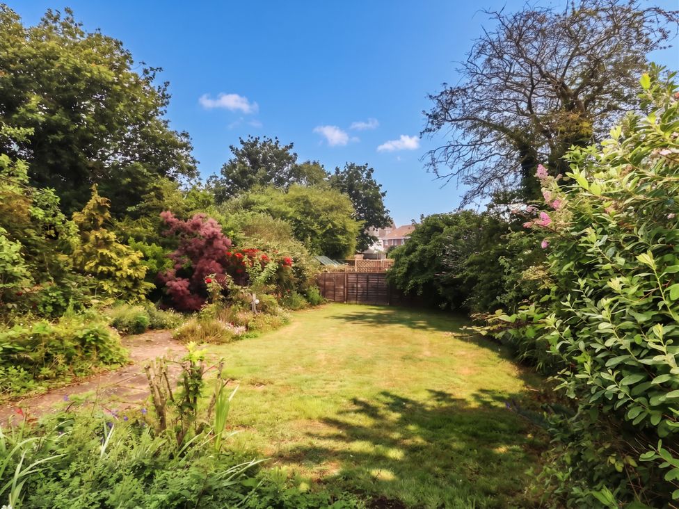 A garden with grass and trees at Tudor Rose in Weymouth
