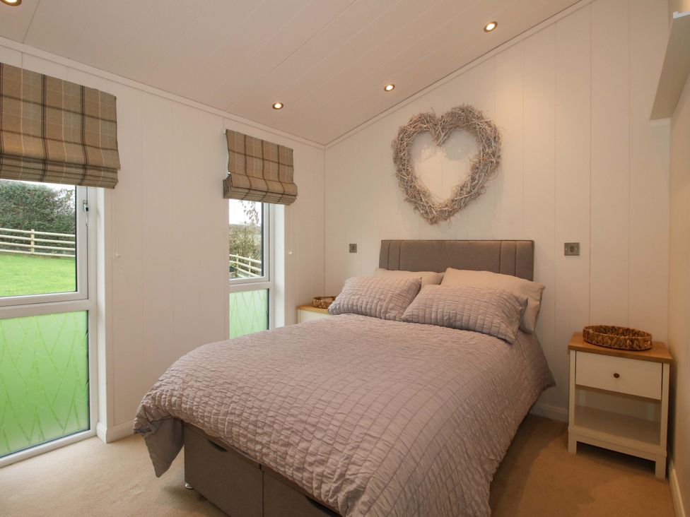 A bedroom with a bed and windows at 5 Hillview Lodges in Cleobury Mortimer