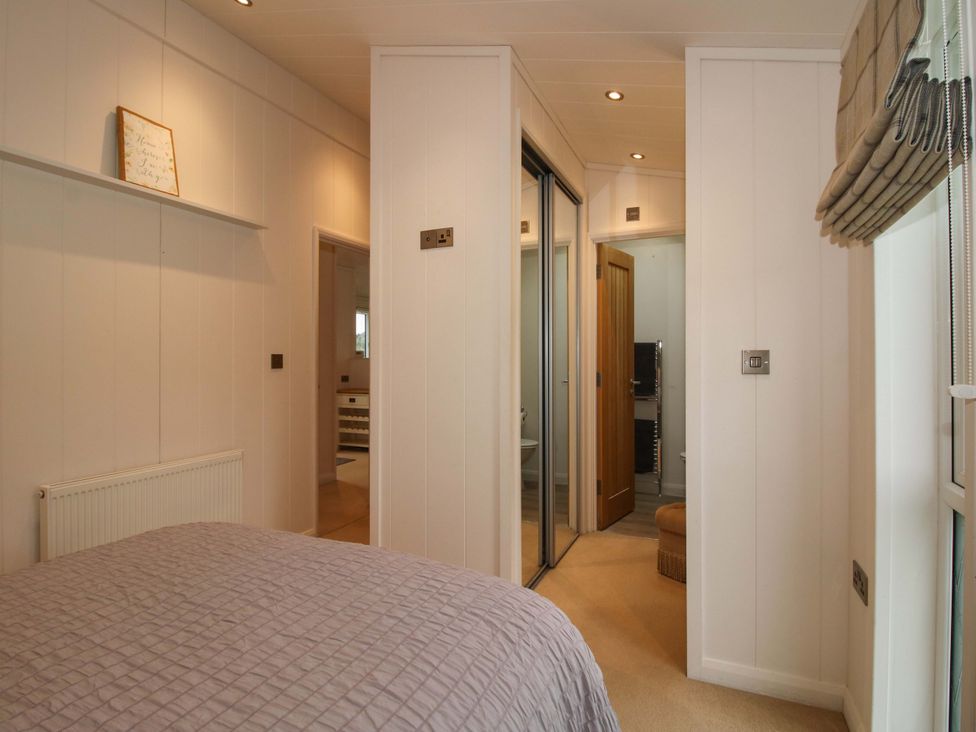 A bedroom with a bed and door leading to a bathroom at 5 Hillview Lodges in Cleobury Mortimer