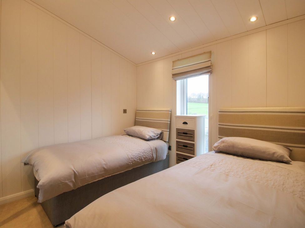 A bedroom with two beds and a window at 5 Hillview Lodges Cleobury Mortimer