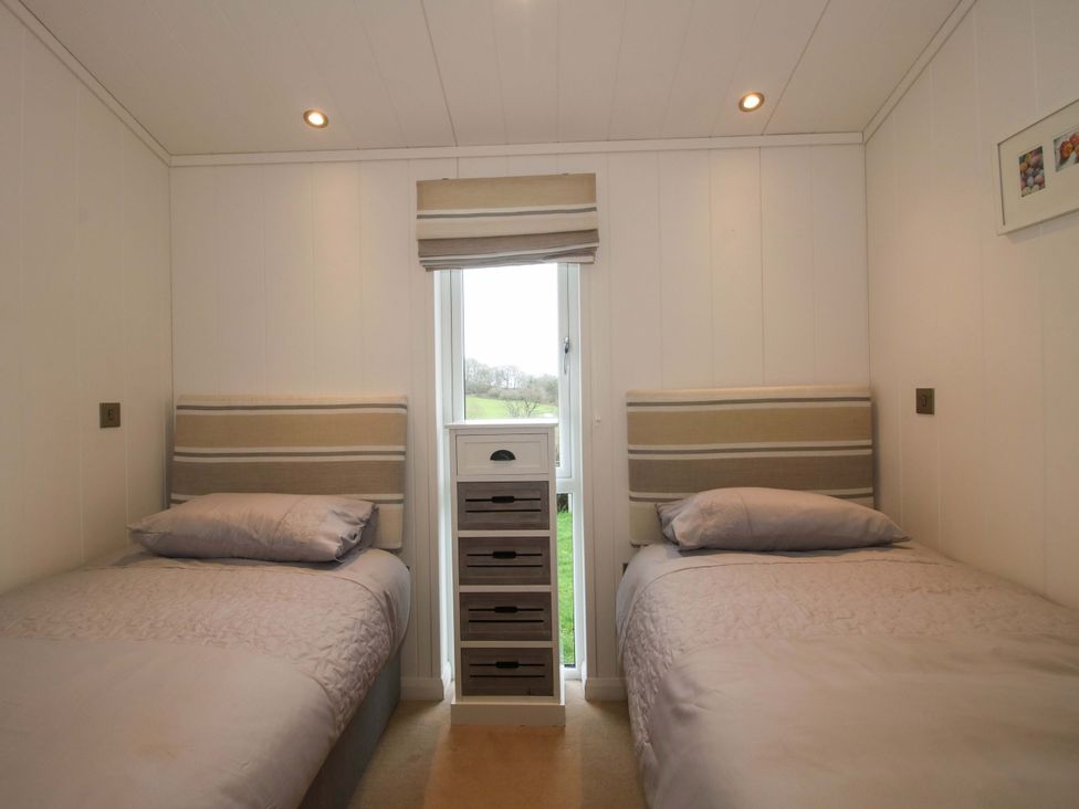 A bedroom with two beds and a window at 5 Hillview Lodges Cleobury Mortimer