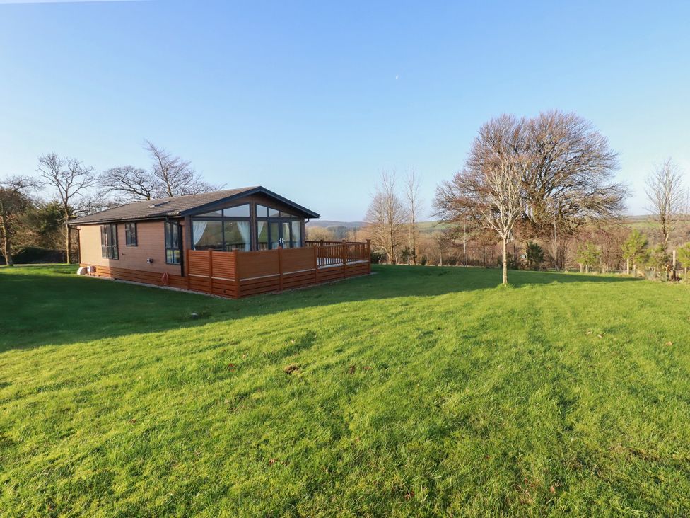 A house with a deck on a lawn at Moorland View