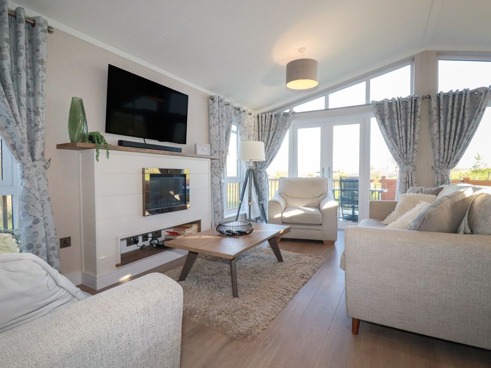 A living room with a television fireplace and sofa at Moorland View 