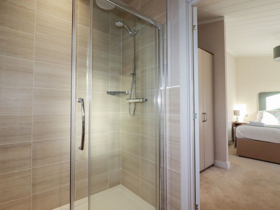 A shower enclosure with glass door and a view of a bedroom at Moorland View in 