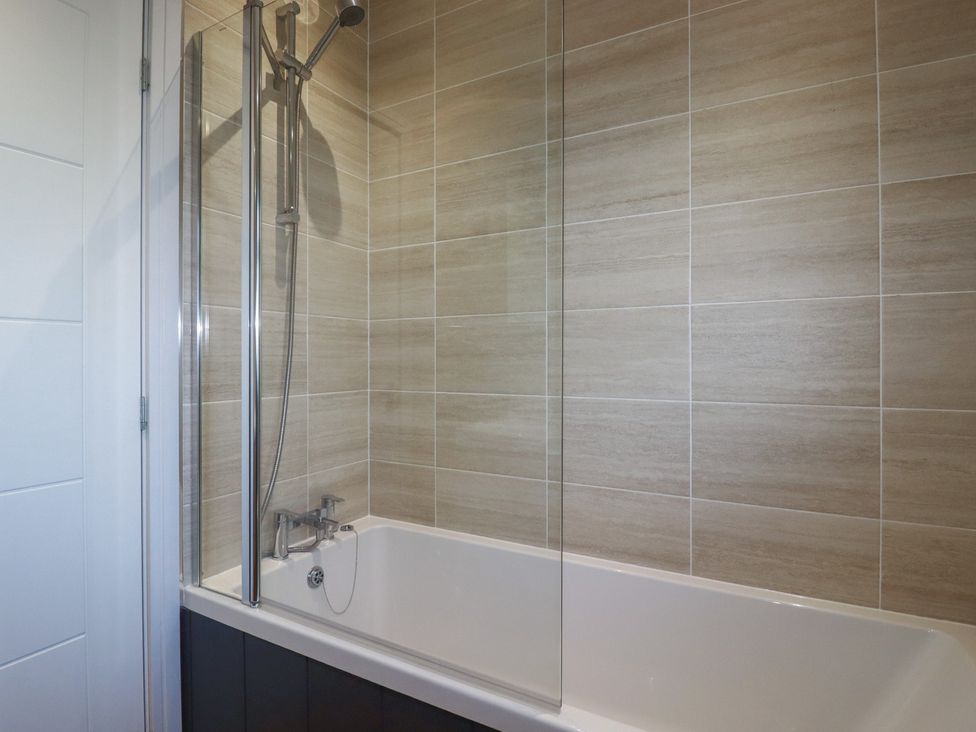 A bathtub with shower panel at Moorland View