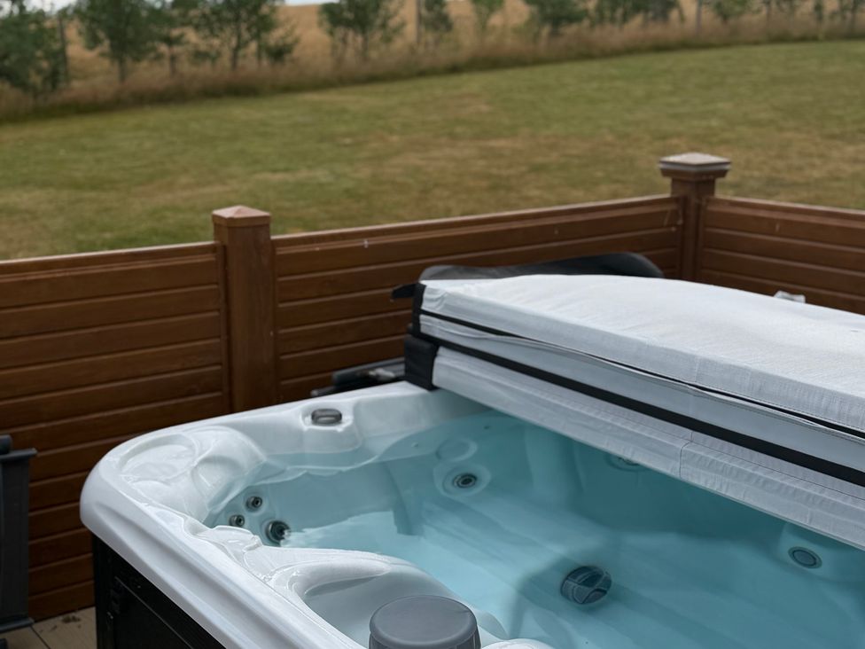 A hot tub with a cover and surrounding fence at Moorland View in Dobwalls