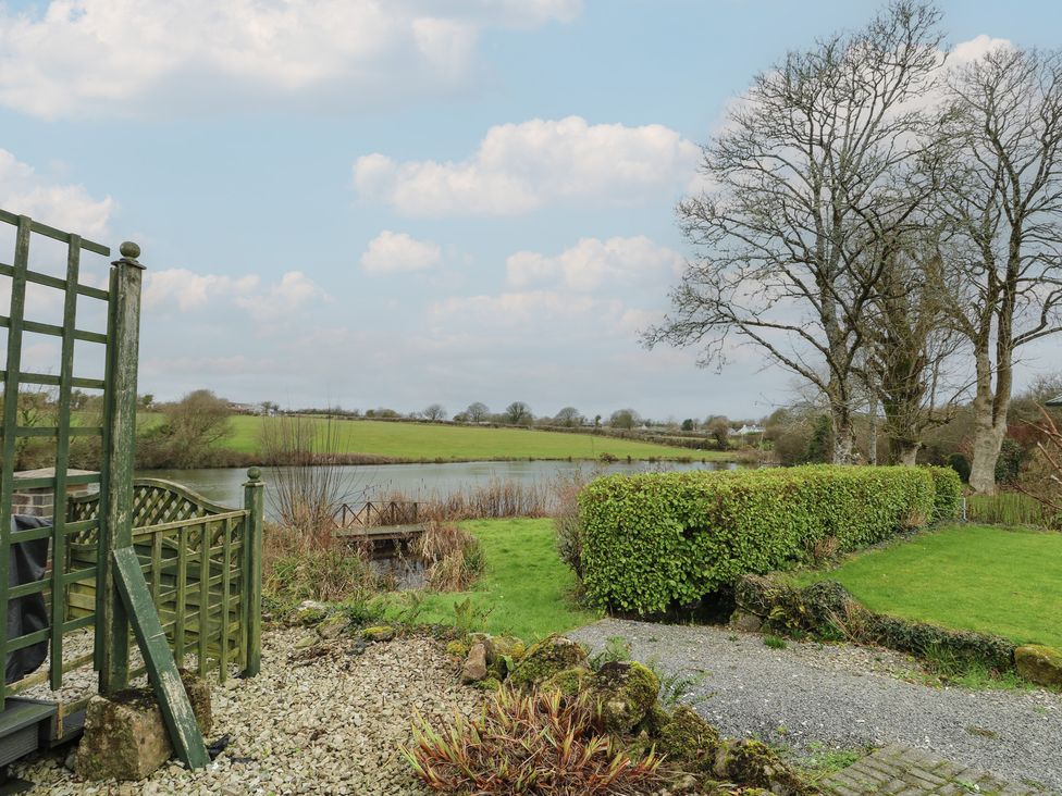 A garden with a lake and trees at Ty Llyn in Brynteg near Benllech