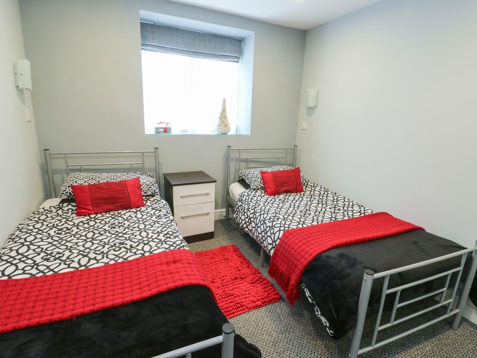 A bedroom with two beds and a nightstand at Ty Llyn in Brynteg near Benllech