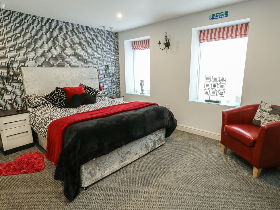 A bedroom with a bed and chair at Ty Llyn in Brynteg near Benllech
