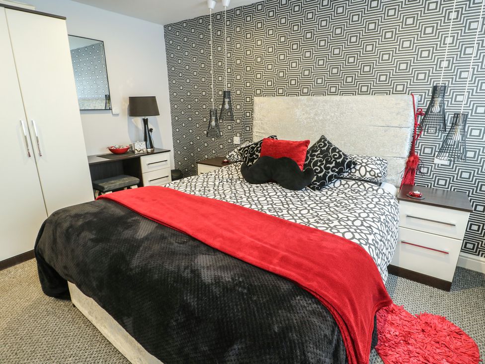 A bedroom with a bed and nightstand at Ty Llyn Brynteg near Benllech