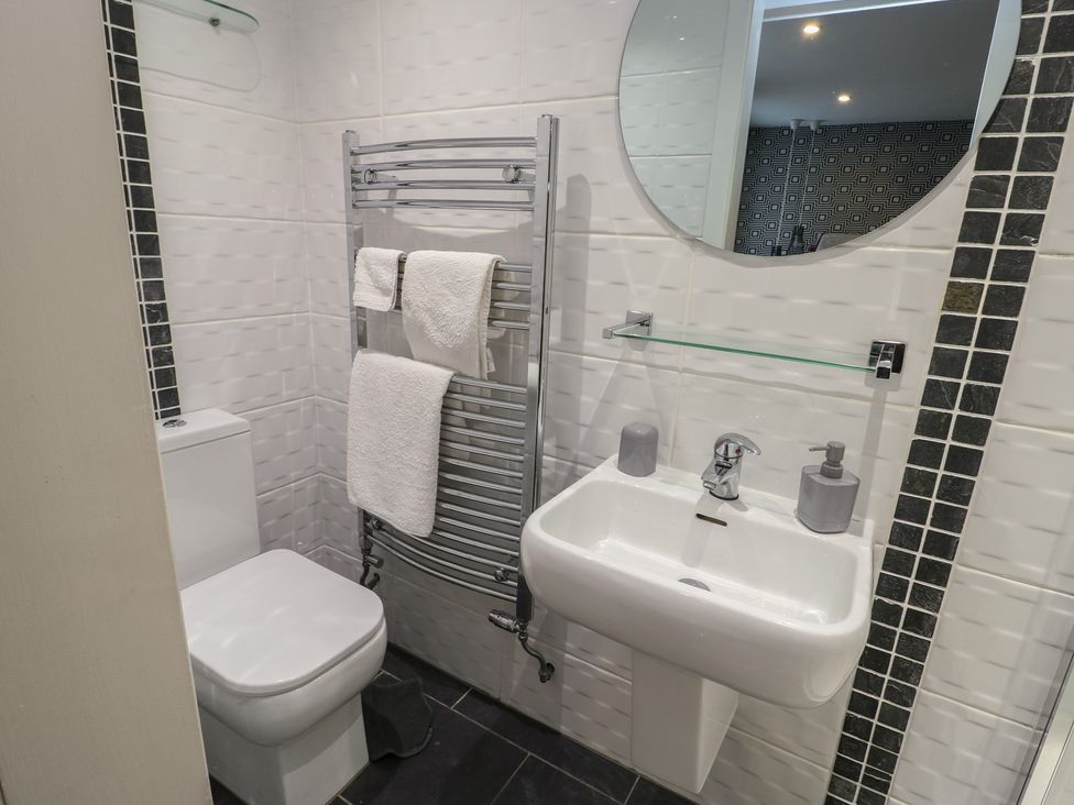 A bathroom with toilet, towel rack, and hand basin at Ty Llyn in Brynteg near Benllech