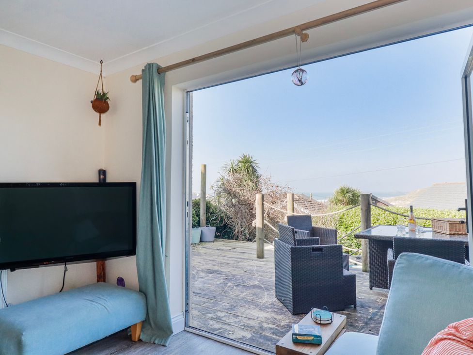 A living room with a view of a deck and chairs at 3A Grannys Lane in Perranporth
