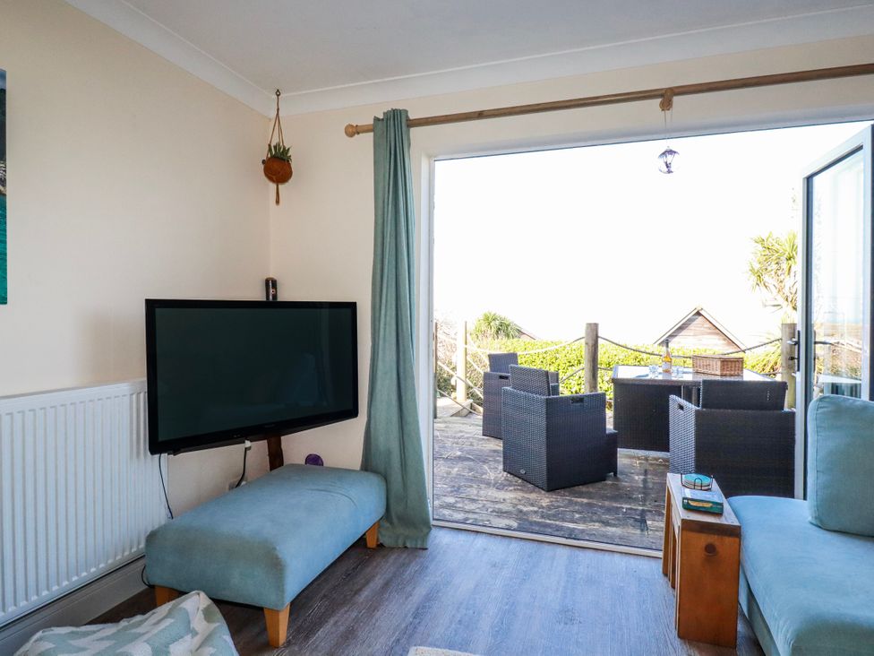 A living room with a television and sliding door leading to outdoor furniture at 3A Grannys Lane Perranporth
